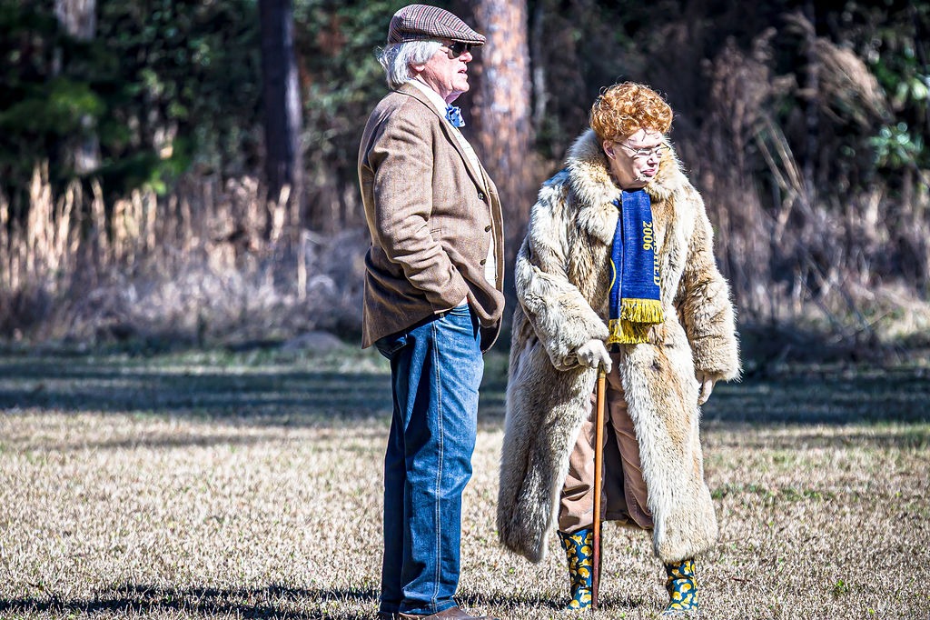 Two people in traditional country clothing standing together in an open field.