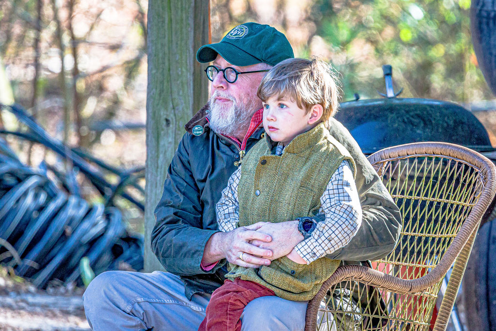 An adult and child seated together outdoors during a club gathering.