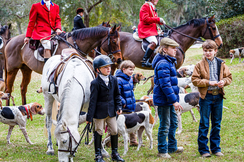 Junior riders and accompanying adults gathered with horses and hounds.