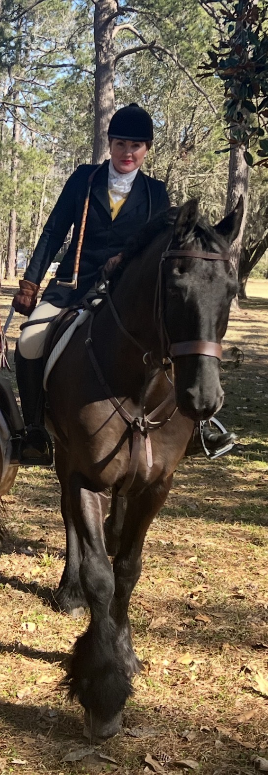 Ashley McCalley mounted on a dark horse in hunt attire