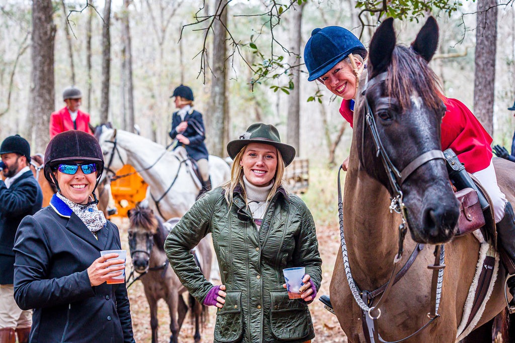 Riders and friends gathered with horses in the woods during a pause in the day.