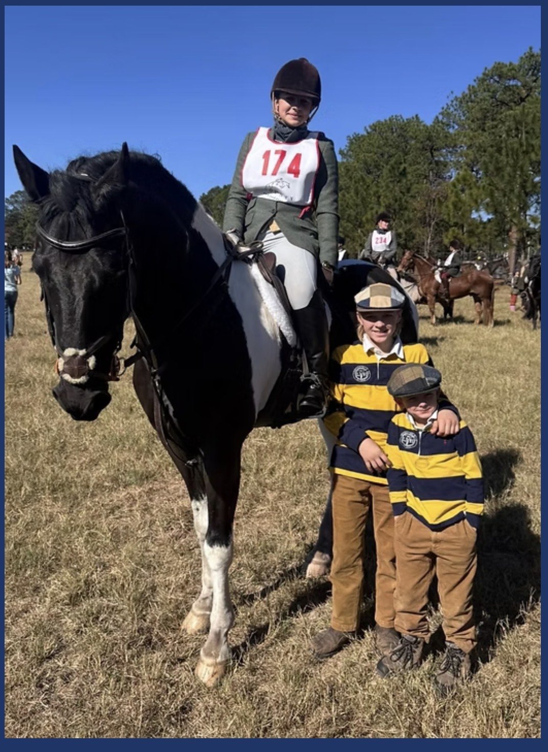 A mounted rider wearing number 174 with children standing beside the horse.